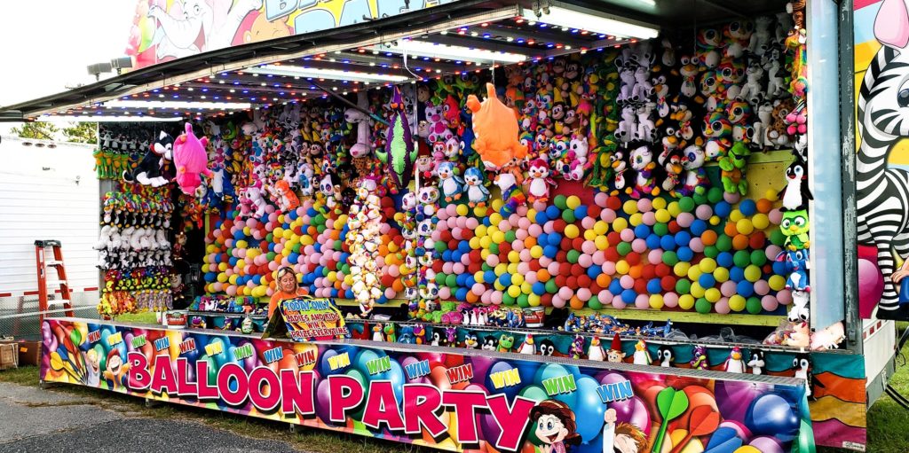 Games of chance with balloons at county fair.