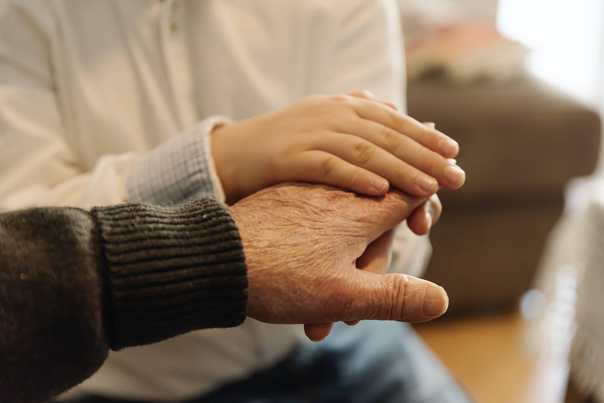 Hand of old person holding hand of kid.