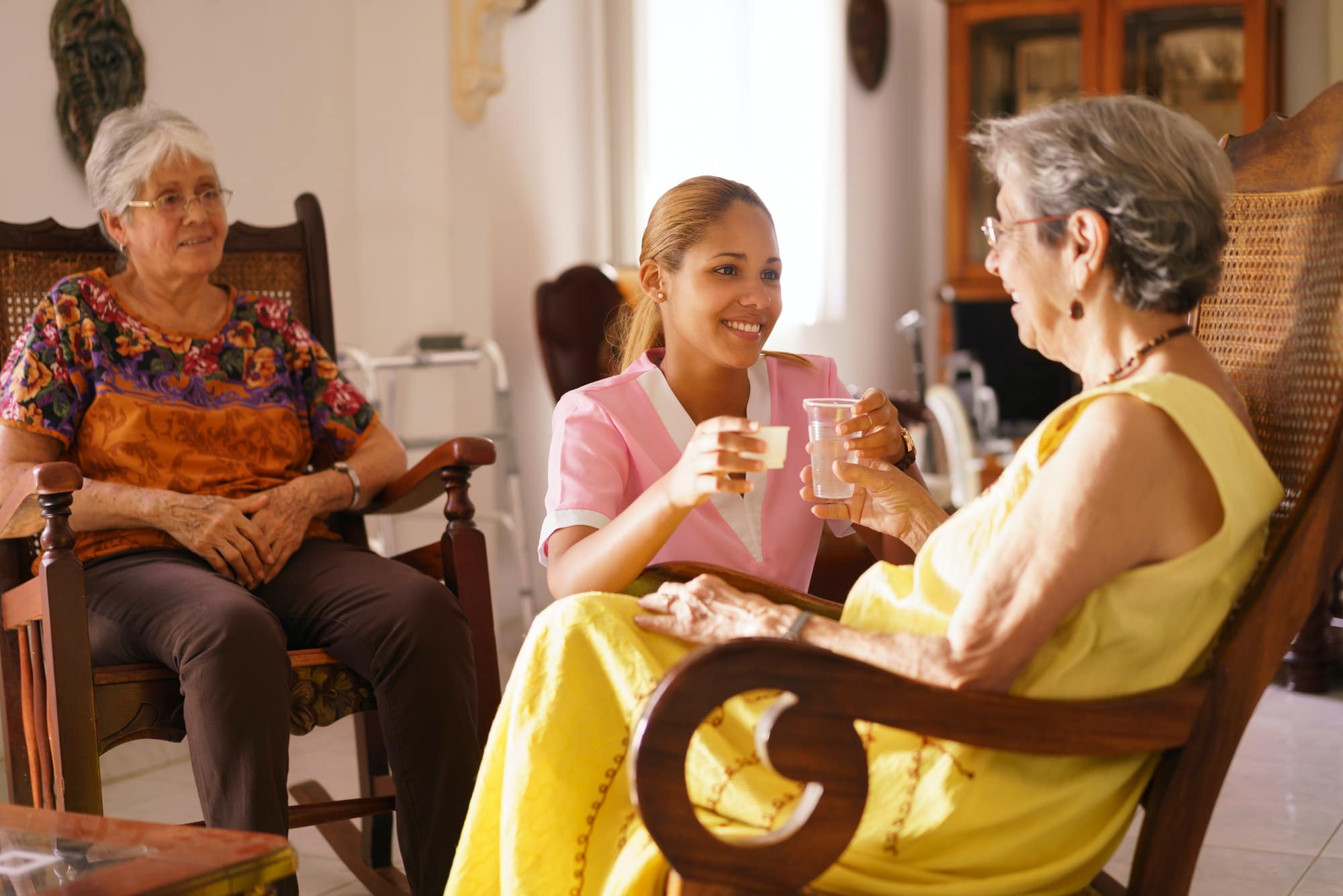 Hospice Nurse Serving Pill Medicine Water To Old Woman