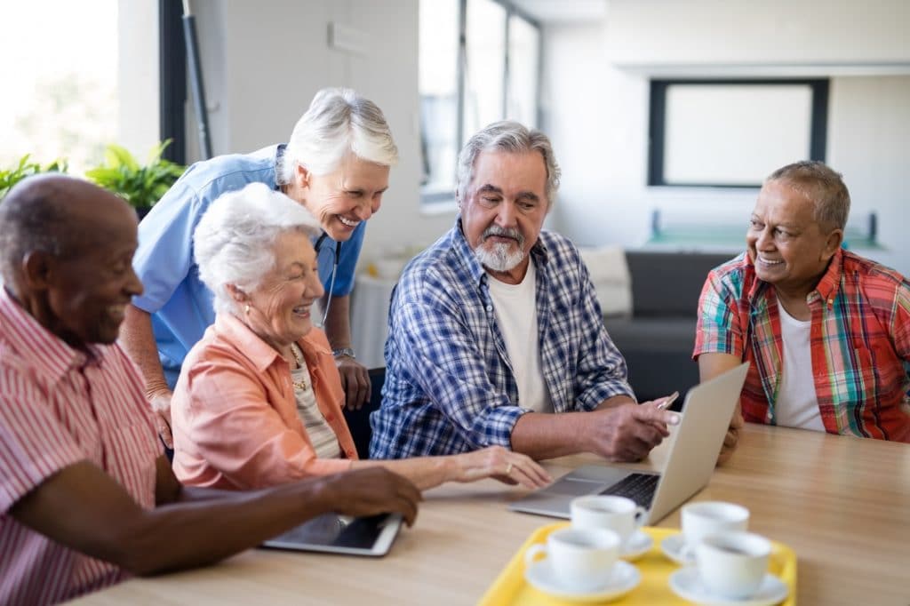 Senior people showing laptop to healthcare worker